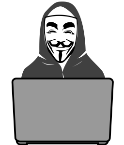 Computer hacker in a Guy Fawkes mask sitting at a laptop